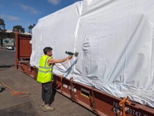 worker shrink wrapping a shipping container