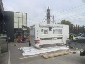 machine being lifted onto a timber base using a crane