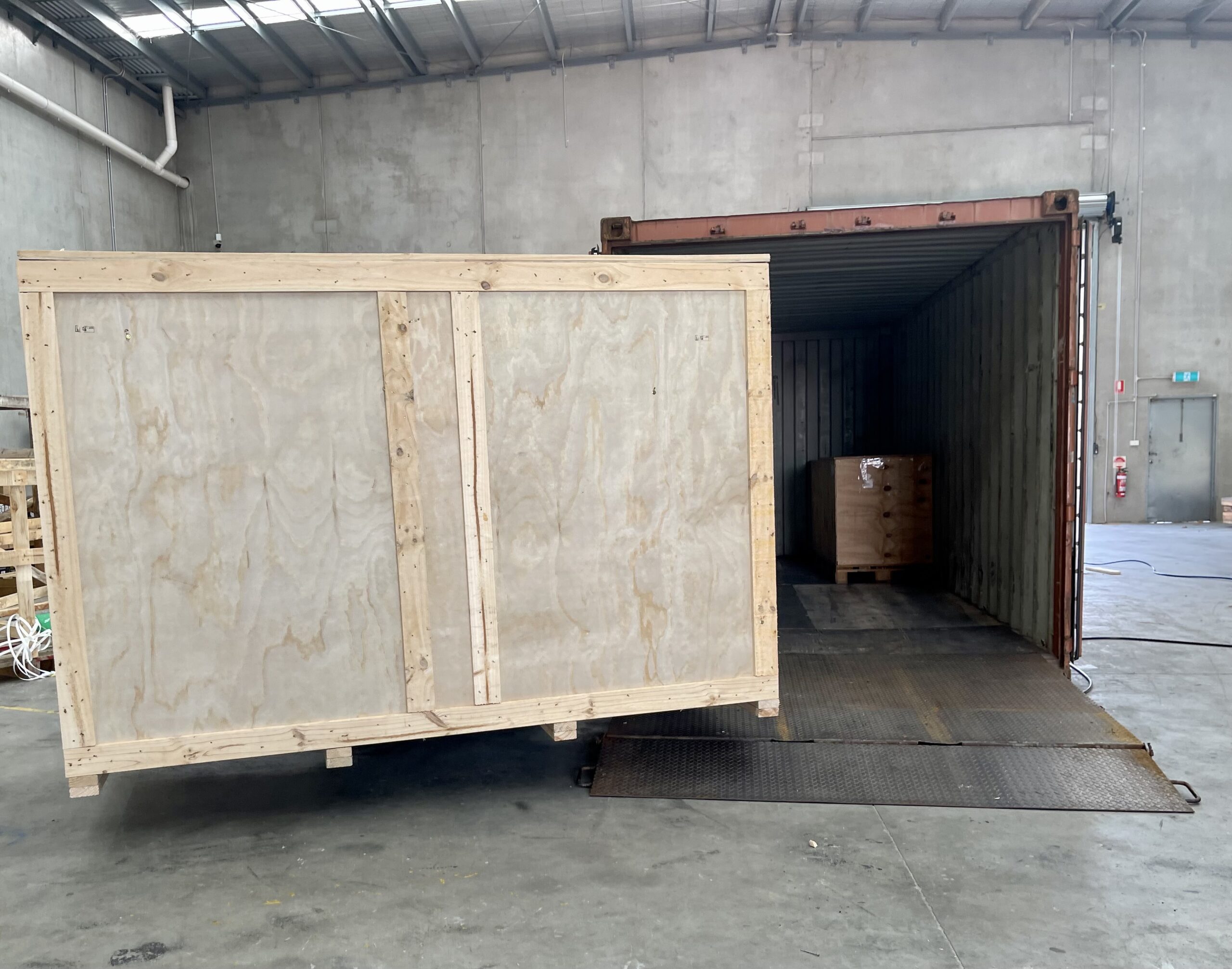 plywood box and shipping container with image of Crate n Pack Solutions logo in background.