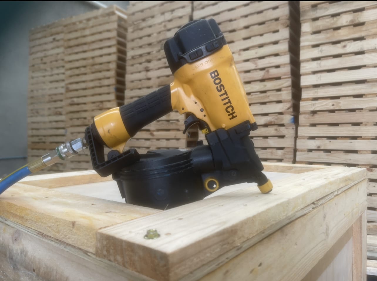 nail gun and pallets stacked in background