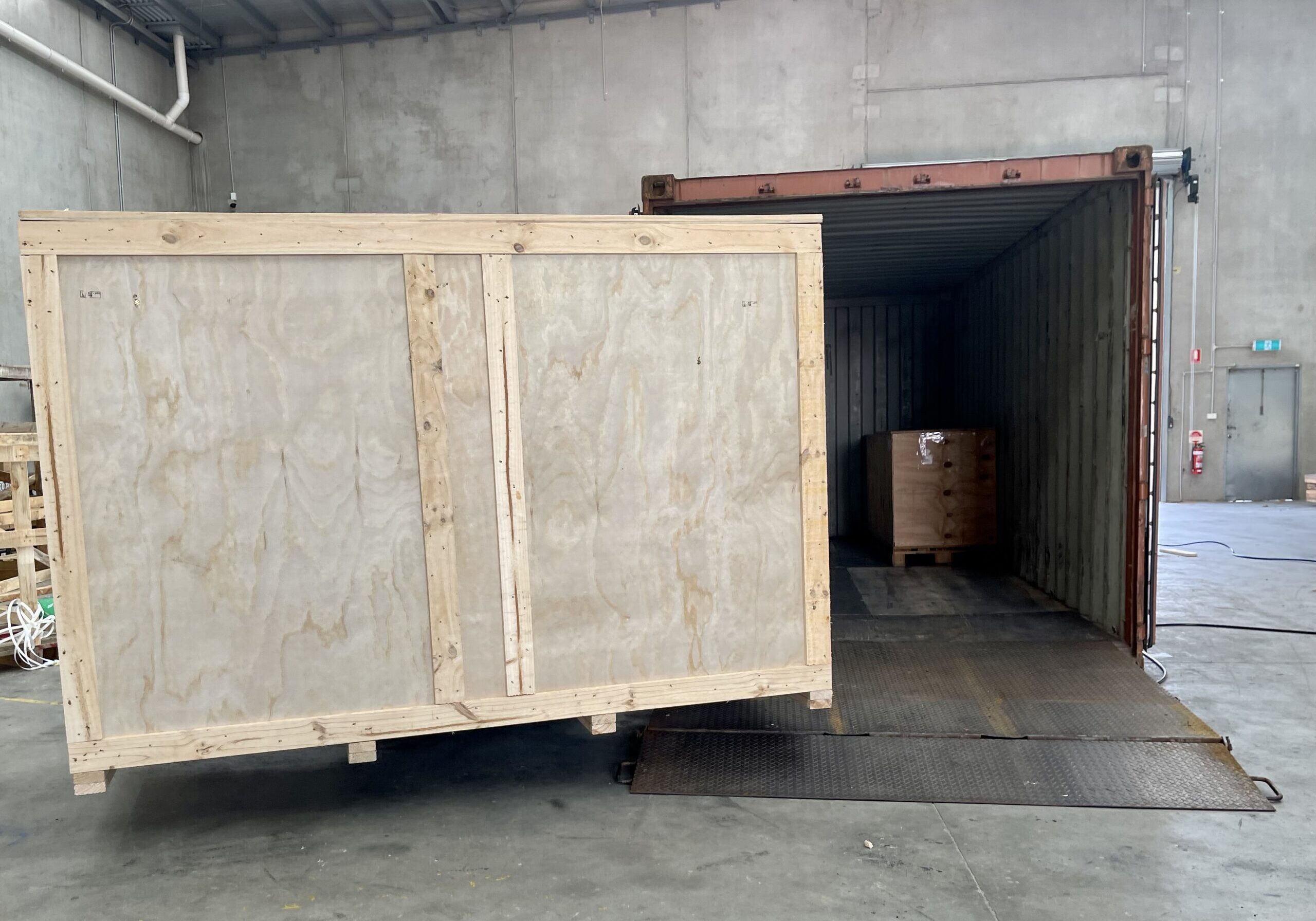 plywood box and shipping container with image of Crate n Pack Solutions logo in background.